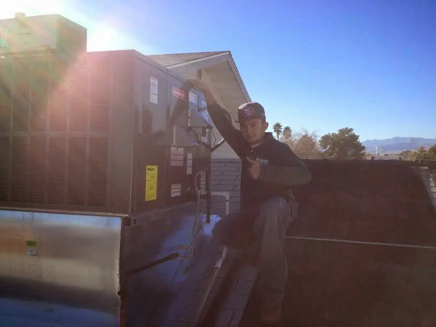 HVAC technician performing Air Duct Cleaning on a rooftop unit in Griswold